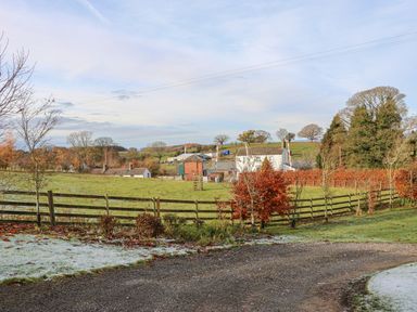 A rural landscape with a gravel path a wooden fence green fields trees and farm buildings at Swift Cottage in Milton near Brampton