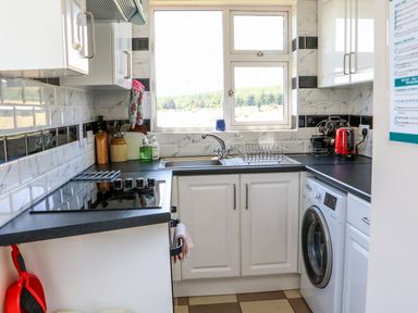 A kitchen with a stove sink washing machine red kettle and window at Clash-Brack Dungarvan County Waterford