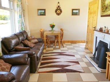 A living room with brown leather sofas a small wooden dining table with chairs and a fireplace at Clash-Brack in Dungarvan County Waterford