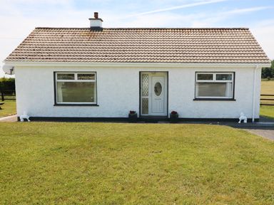 A white single-story house with two windows and a central door on a grassy lawn at Clash-Brack in Dungarvan County Waterford