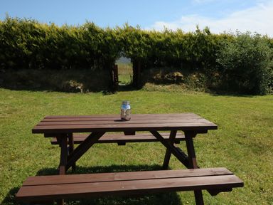 An outdoor wooden picnic table with benches on grass and a glass jar on the table at Clash-Brack in Dungarvan County Waterford