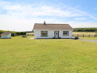 A single story house with a large grass lawn and a picnic table at Clash-Brack in Dungarvan County Waterford