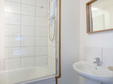 A bathroom with a shower, bathtub, sink, and mirror at Tidewood in Polzeath