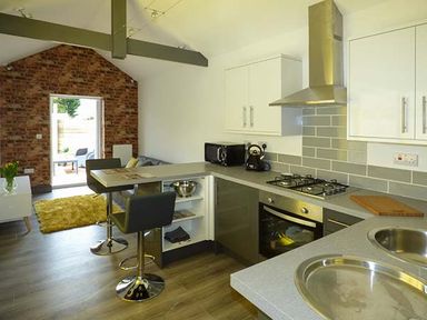 A kitchen and dining area with bar stools and cooking appliances at White Cottage Annexe in Tenby