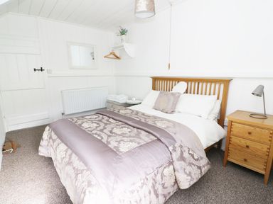 A bedroom with a double bed wooden headboard bedside table lamp and folded towels on an ottoman at Penglanowen Fawr in Llangwyryfon near Aberystwyth