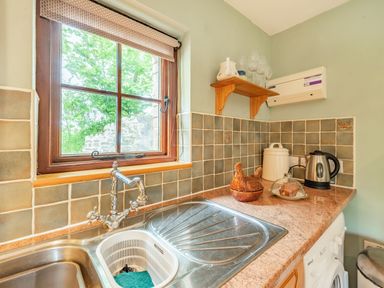 A kitchen corner with a sink a window a kettle and tiled backsplash at Cilwen Fach in Cynwyl Elfed