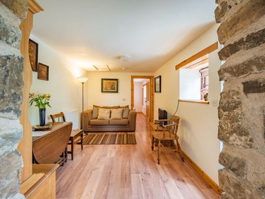 A living room with a sofa table with flowers chairs a floor lamp and framed pictures at Cilwen Fach in Cynwyl Elfed