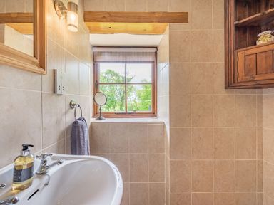 A bathroom with a sink a soap dispenser a towel a mirror and a window with a view at Cilwen Fach in Cynwyl Elfed