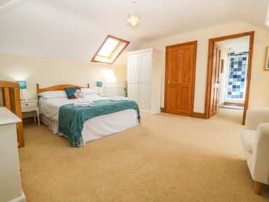 A bedroom with a double bed bedside tables blue lamps wardrobe and an armchair at Fferam Y Llyn in Rhosgoch near Cemaes Bay