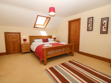 A bedroom with wooden bed and bedside tables under a skylight window at Fferam Y Llyn in Rhosgoch near Cemaes Bay
