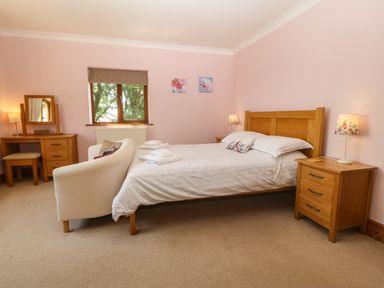 A bedroom with a wooden bed table lamps and a dressing table at Fferam Y Llyn in Rhosgoch near Cemaes Bay