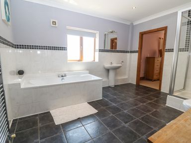 A bathroom with a bathtub sink shower and tiled floor at Fferam Y Llyn Rhosgoch near Cemaes Bay