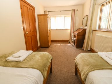 A bedroom with two single beds and a wooden wardrobe at Fferam Y Llyn in Rhosgoch near Cemaes Bay