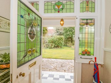 An open front door with stained glass leading to a garden with stone paving at West Ridge in Boscombe