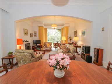 A living room with sofa chairs a wooden table and flowers in a vase at West Ridge in Boscombe