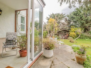 A garden with potted plants a patio set and a wooden shed at West Ridge in Boscombe