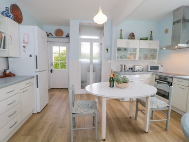 A kitchen with a round table and two chairs a refrigerator cabinets and kitchen appliances at West Ridge in Boscombe