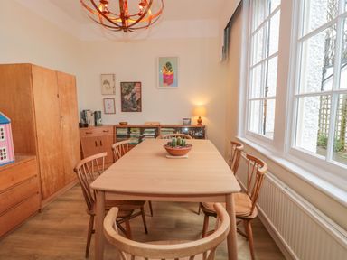 A dining room with a wooden table and chairs a wooden cabinet books on a shelf and framed pictures on the wall at West Ridge in Boscombe