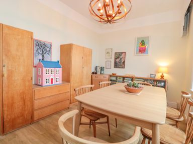 A dining room with a wooden table and chairs a large wooden cupboard and a chest of drawers with a model house on top at West Ridge in Boscombe