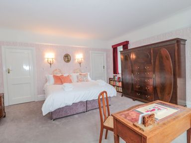 A bedroom with a double bed, wooden wardrobe, wooden desk with chair, and bookshelf by a window at West Ridge in Boscombe