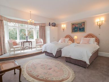 A bedroom with two beds a round rug and a sitting area by a large window at West Ridge in Boscombe
