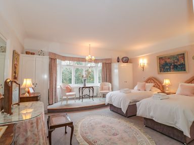 A bedroom with two single beds a round rug and a seating area with chairs and a table at West Ridge in Boscombe