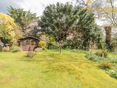 A garden with grass trees a wooden shed and outdoor furniture at West Ridge in Boscombe