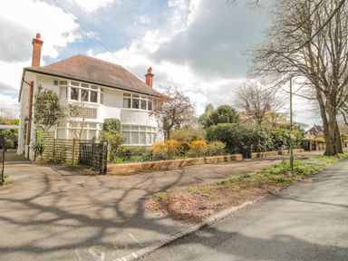 A detached house with a garden and trees along a street at West Ridge in Boscombe