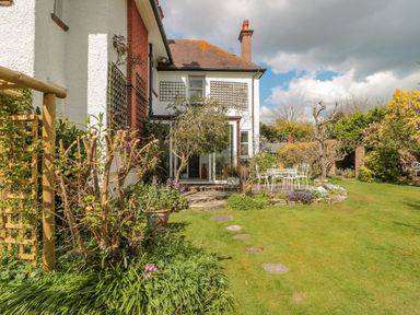 A garden with a patio area and outdoor furniture beside a two story house at West Ridge in Boscombe
