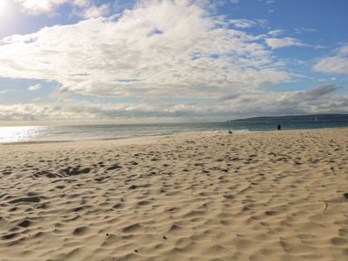 A sandy beach with the ocean and cloudy sky in the background at West Ridge in Boscombe
