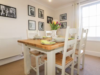 A dining room with a wooden table set with plates glasses and a vase of flowers at Tremanners in St  Agnes