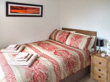 A bedroom with a double bed with patterned bedding and folded towels on the bed at Owl Cottage in Napton-on-the-Hill near Southam