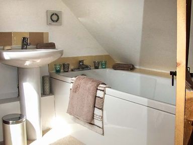 A bathroom with a pedestal sink a bathtub and towels at Owl Cottage in Napton-on-the-Hill near Southam