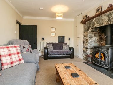 A living room with sofas a wooden coffee table and a wood burning stove at Duddon Cottage in Broughton-in-Furness