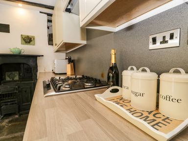 A kitchen countertop with a gas stove knife block and canisters labeled tea sugar and coffee at Duddon Cottage in Broughton-in-Furness