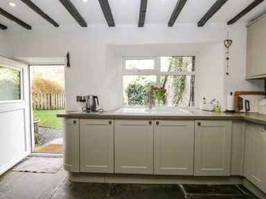 A kitchen with a sink below a window and a door leading outside at Duddon Cottage in Broughton-in-Furness