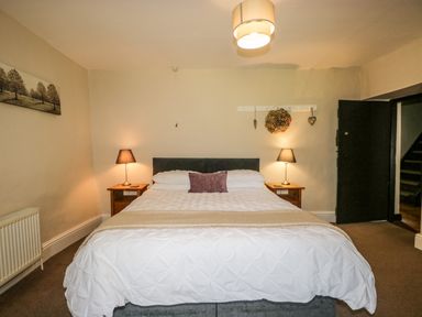 A bedroom with a double bed two bedside tables with lamps and a painting on the wall at Duddon Cottage in Broughton-in-Furness