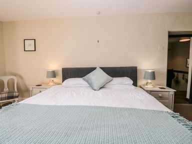 A bedroom with a bed with white linens and blue throw at Duddon Cottage in Broughton-in-Furness