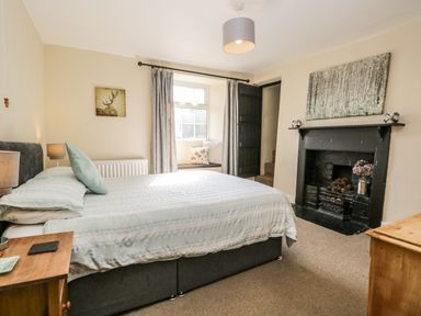 A bedroom with a bed a fireplace and a window seat at Duddon Cottage in Broughton-in-Furness