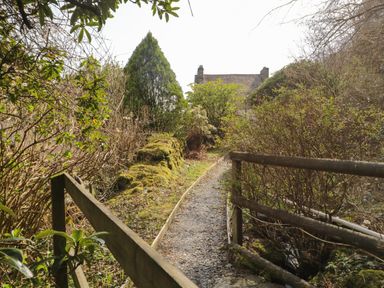 A garden path with wooden railings and bushes leading to a house at Duddon Cottage in Broughton-in-Furness