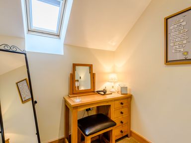 A dressing table with a mirror lamp and stool under a skylight at The Stables in Llanfair Caereinion near Welshpool
