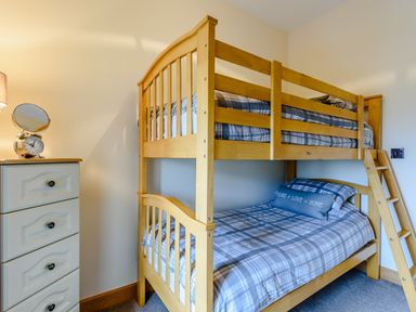 A bedroom with a wooden bunk bed and a small chest of drawers with a clock and lamp at The Stables in Llanfair Caereinion near Welshpool