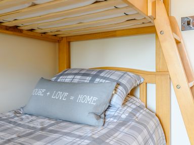 A bunk bed with plaid bedding and a pillow with a house love home quote at The Stables in Llanfair Caereinion near Welshpool
