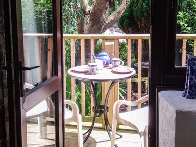 A small outdoor table set with teapot and cups on a wooden deck with two white chairs at Groom Cottage Poughill near Bude