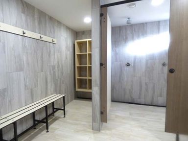 A locker room with a bench coat hooks and shelving units at Groom Cottage in Poughill near Bude