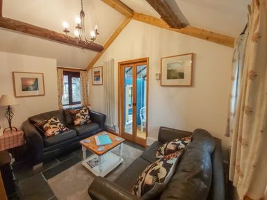 A living room with two leather sofas a wooden coffee table and framed pictures on the walls at Groom Cottage in Poughill near Bude