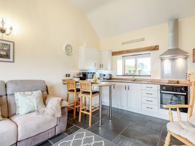 A kitchen with white cabinets wooden countertops and a small dining table with two chairs at The Granary in Llanfair Caereinion near Welshpool