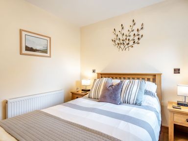 A bedroom with a double bed striped bedding bedside tables with lamps and wall decorations at The Granary in Llanfair Caereinion near Welshpool