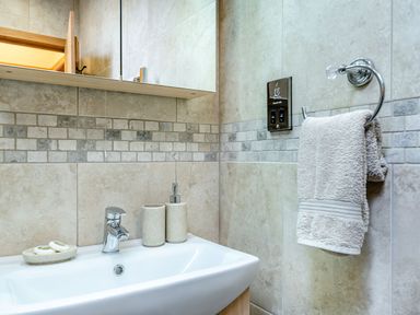 A bathroom sink with a faucet soap dispenser toothbrush holder and hand towel at The Granary in Llanfair Caereinion near Welshpool