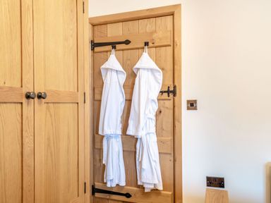 A wooden door with two white bathrobes hanging and a wooden wardrobe beside it at The Granary in Llanfair Caereinion near Welshpool